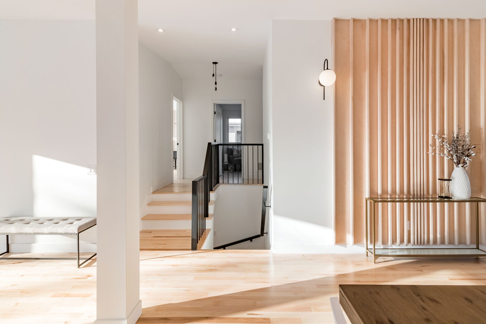 Un salon avec parquet et un escalier en arrière plan.