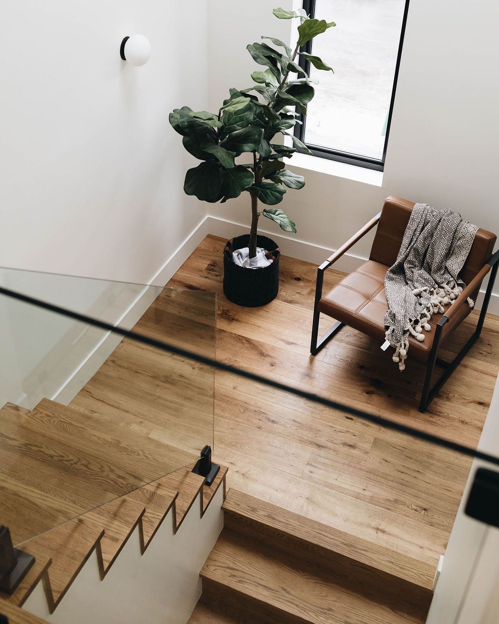 Un escalier en bois avec une chaise et une plante en pot