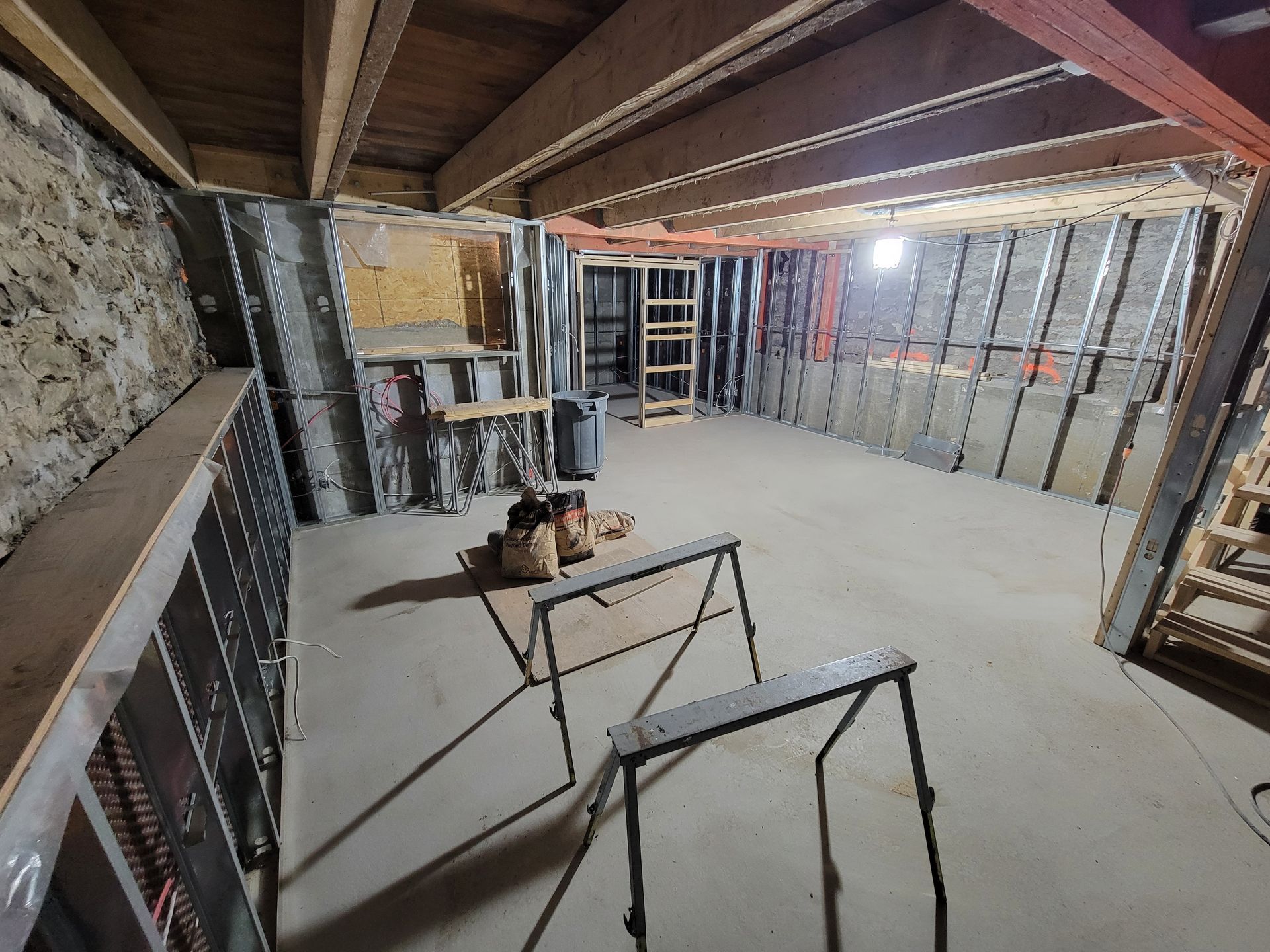 Intérieur d'un sous-sol en rénovation avec cloisons vitrées et plancher de béton.