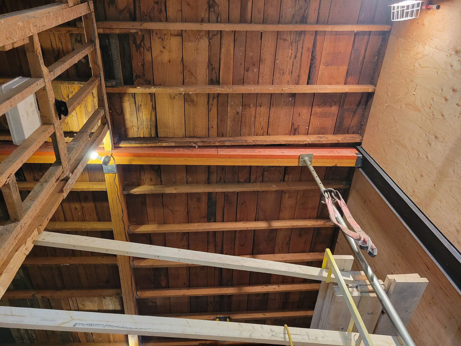 Intérieur d'une structure en bois avec poutres, solives et éléments de charpente lors de travaux de construction.