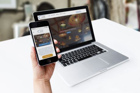 A person is holding a cell phone in front of a laptop computer.