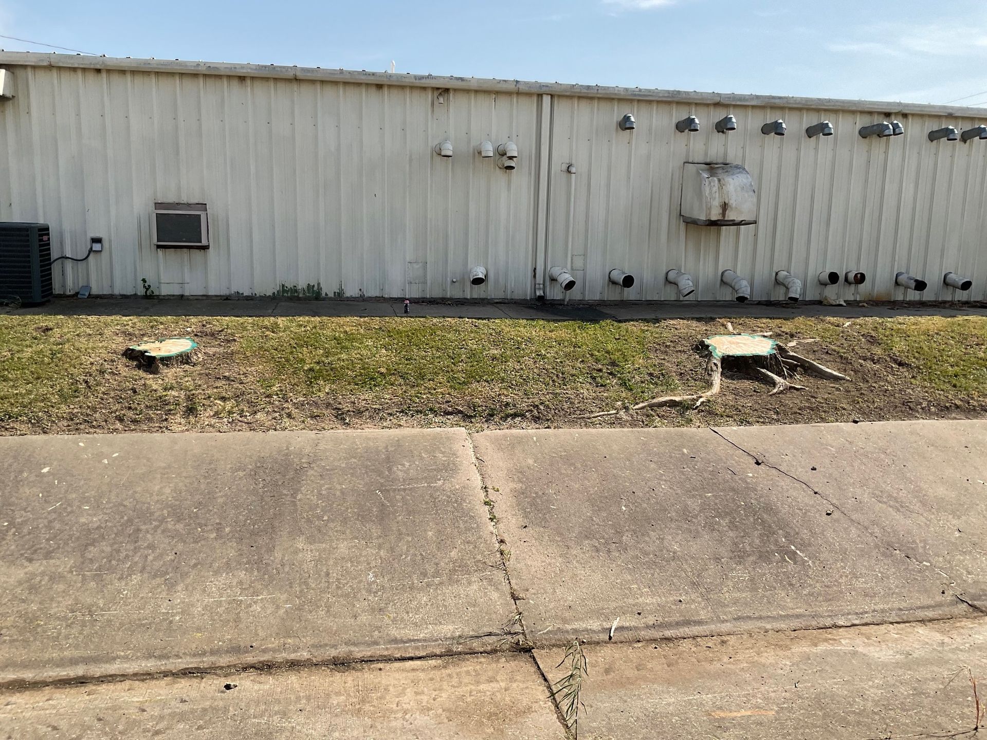 A white building with a concrete sidewalk in front of it