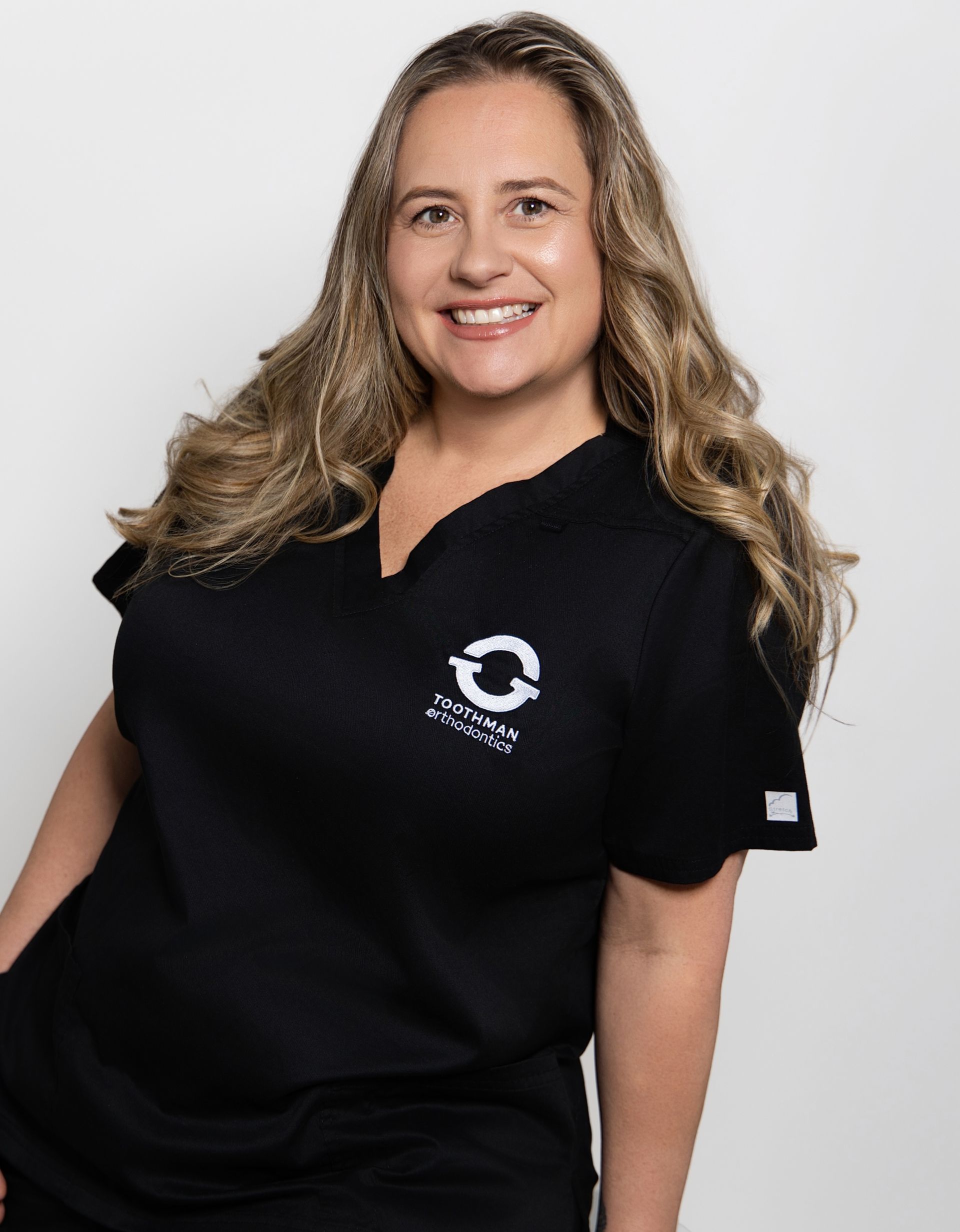 Woman smiling in a black polo shirt against a light gray background
