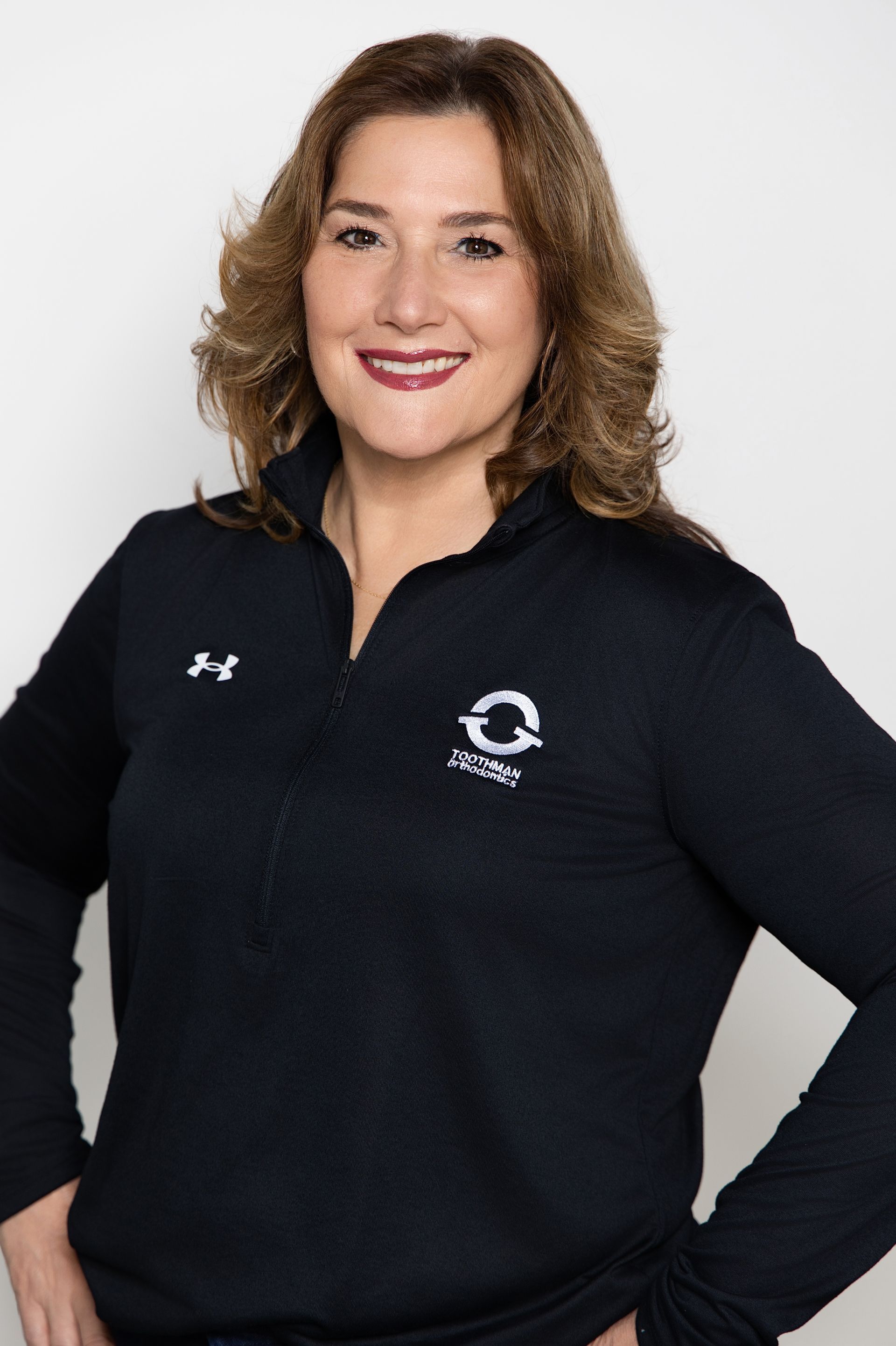 Woman in a black pullover smiling against a white background.