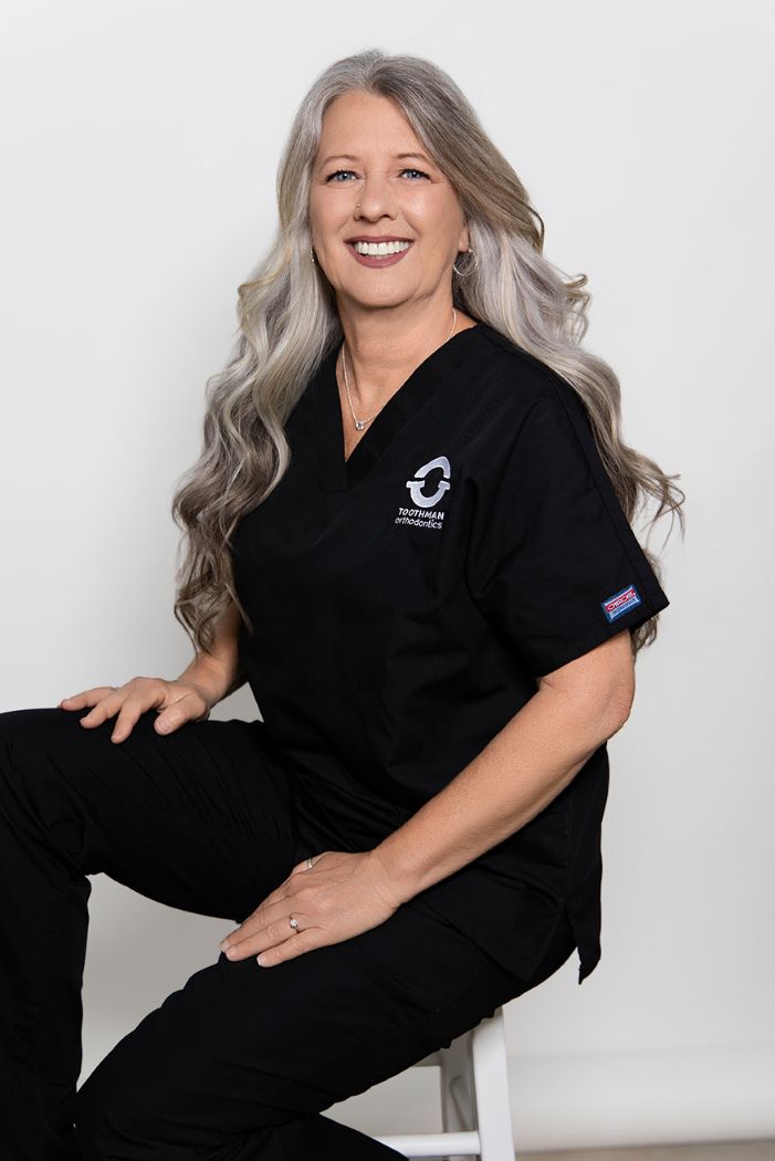Smiling professional in black polo, seated against a white background.