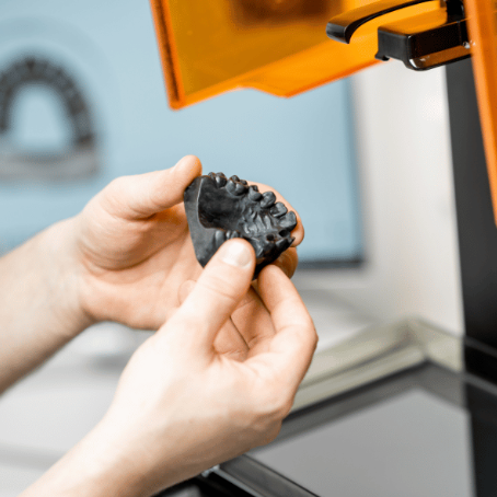A person is holding a model of a tooth in their hands