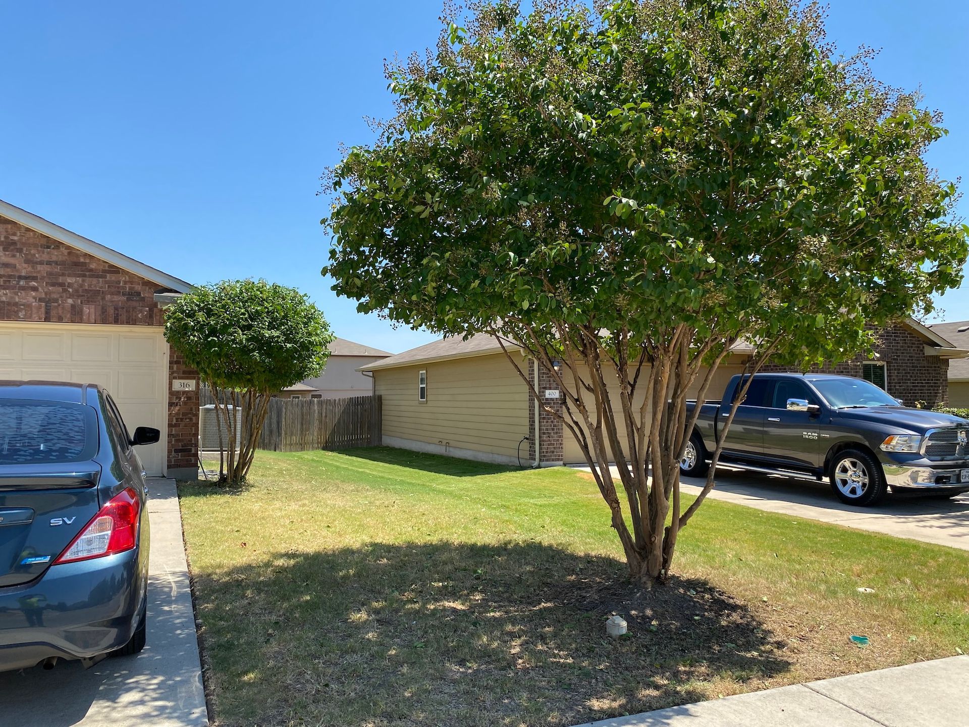 a car is parked in front of a house next to a tree .