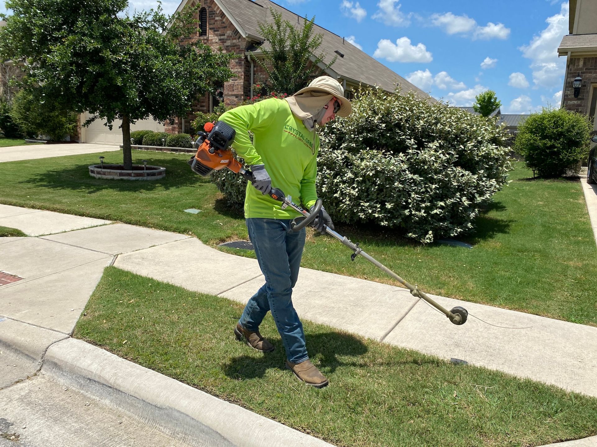 a man is using a lawn mower to cut the grass in front of a house .