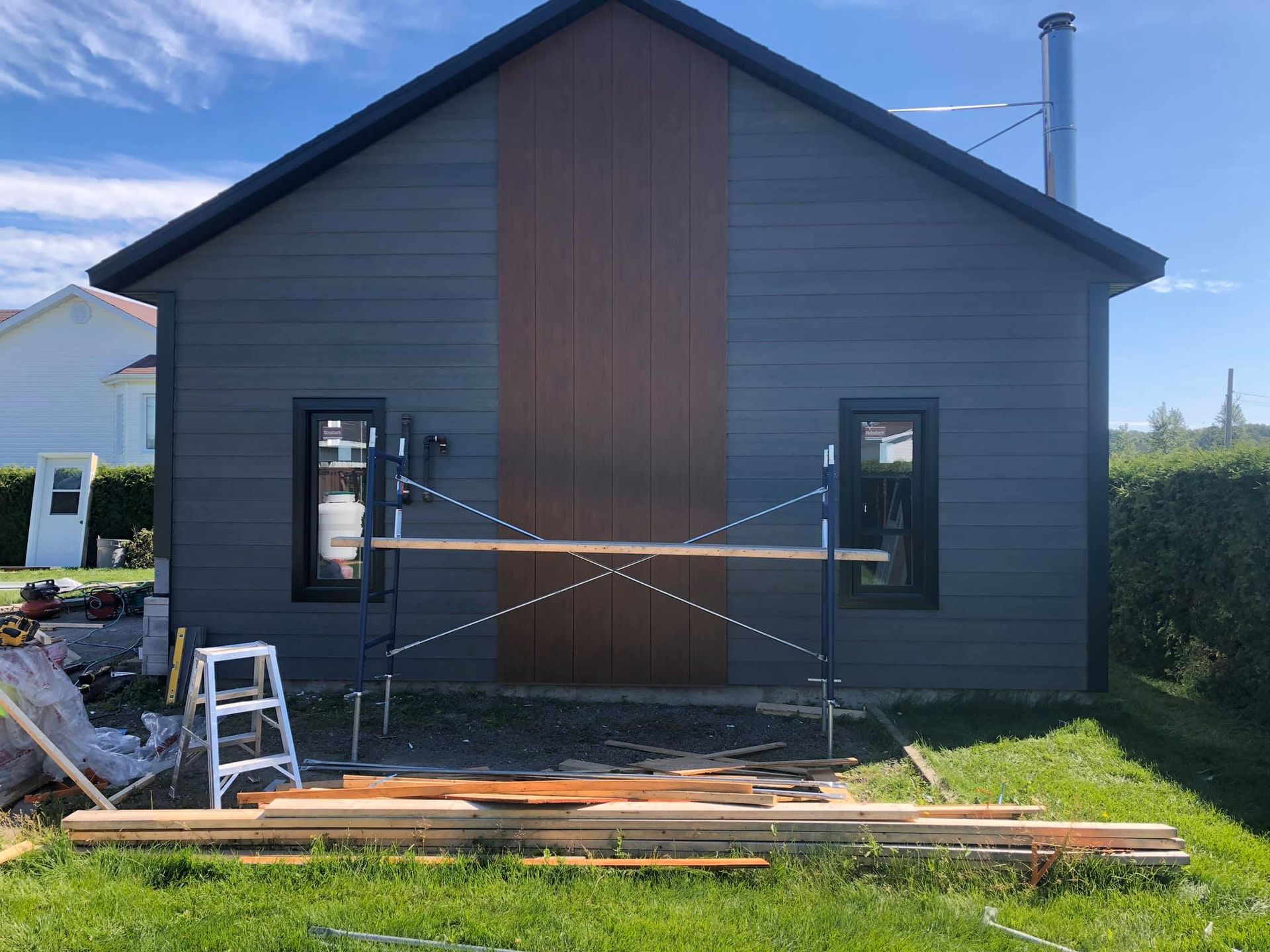 Une maison est en train d'être peinte dans une cour avec un échafaudage devant elle.