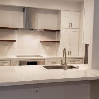 Modern white kitchen with island countertop, sink, and built-in cabinets and shelves