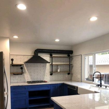 Modern kitchen with blue cabinets, white countertops, black hood, and white subway tile backsplash