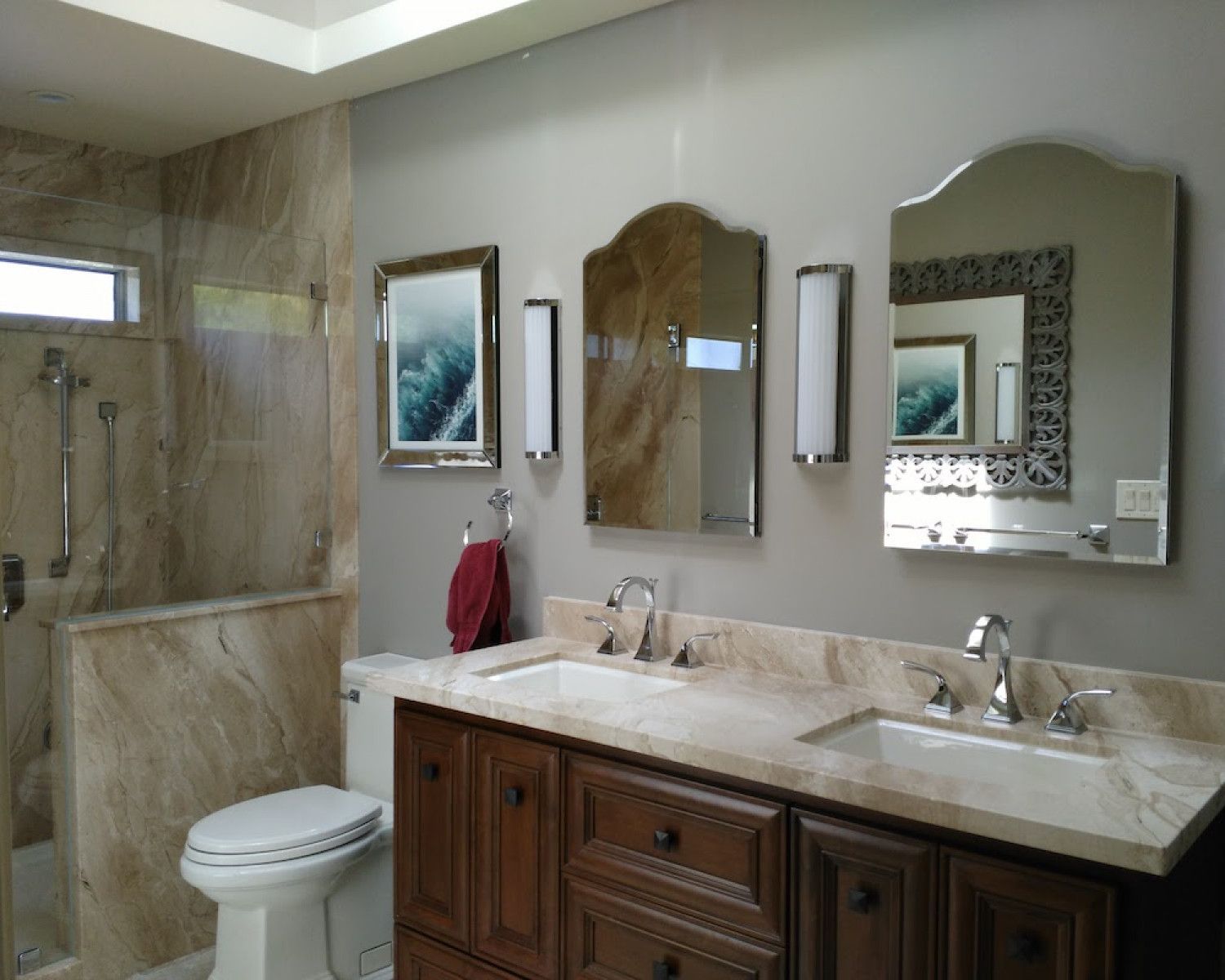 Elegant bathroom with double vanity, large mirrors, marble countertop, and tiled shower.