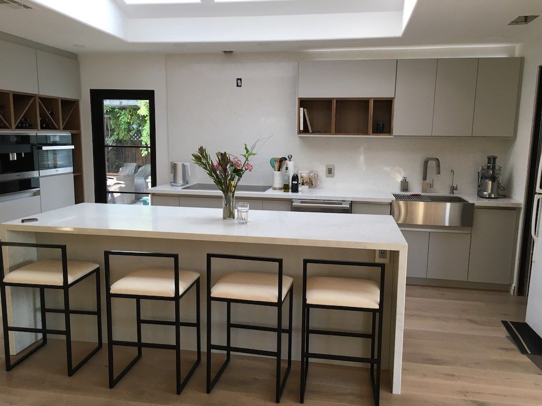 Modern kitchen with white island, four stools, stainless sink, and open shelving
