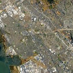 Satellite view of a dense coastal city with roads, buildings, and a harbor