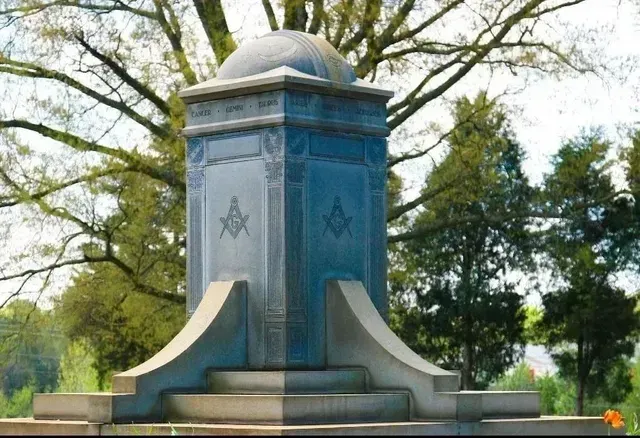 Blue stone memorial monument in a park with trees and grass