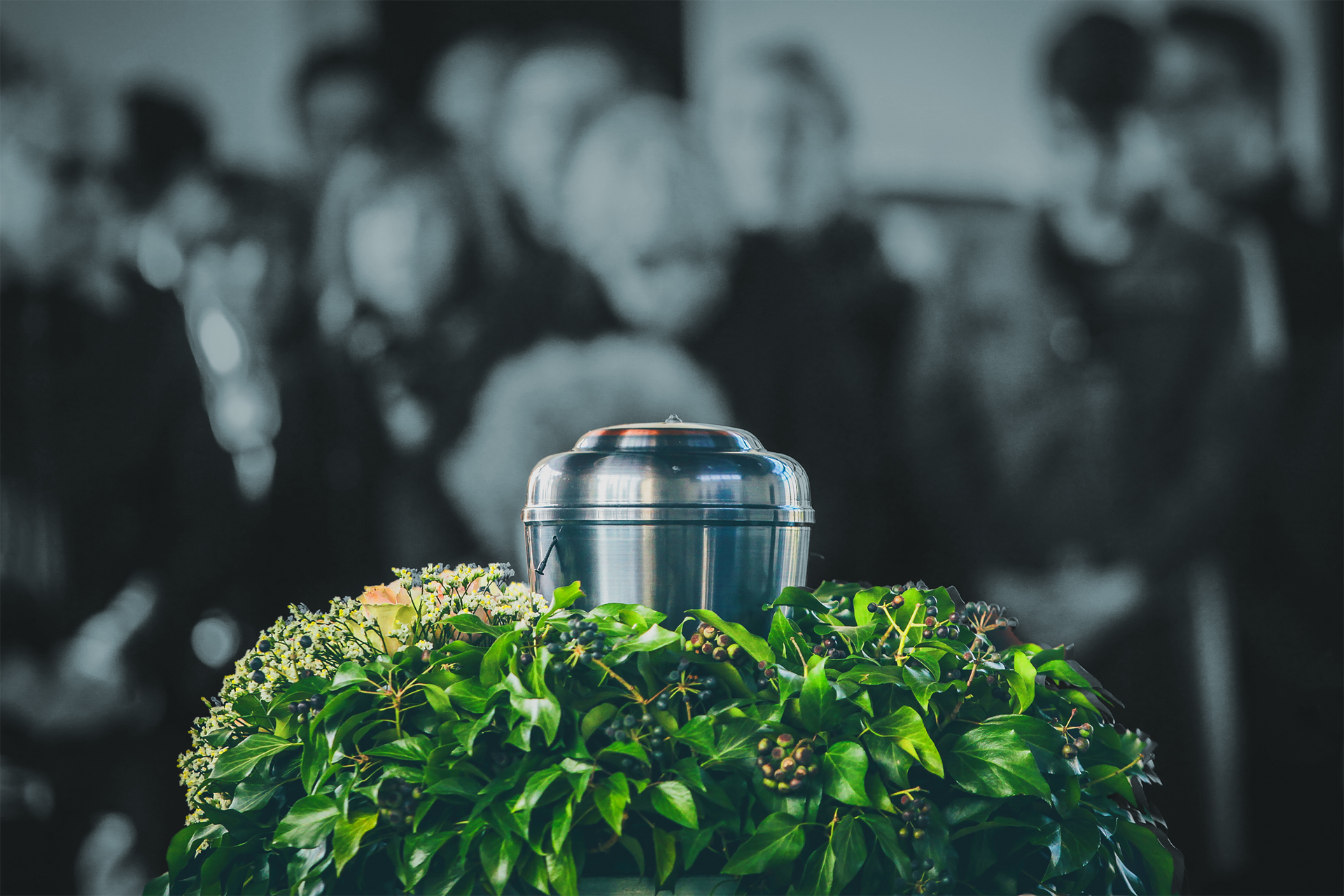 Chrome urn on green foliage with blurred people in the background