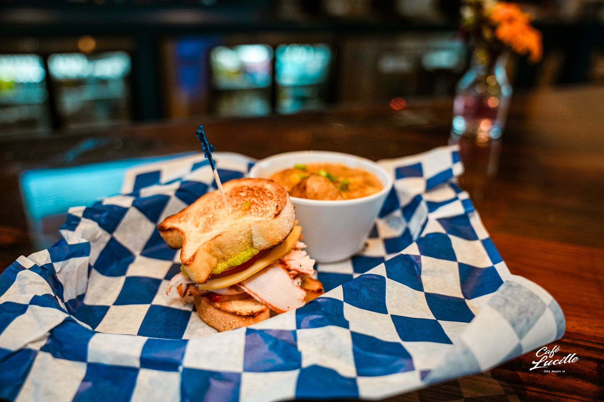 Sandwich and soup in a basket on a table. The setting is a restaurant or bar, with a blurred background.