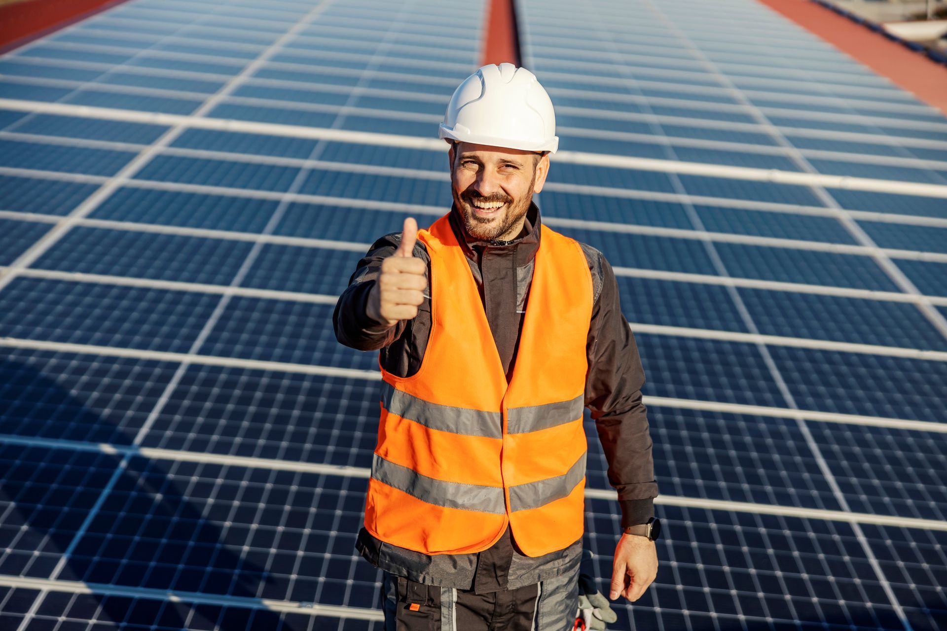 A man is giving a thumbs up in front of a solar panel field.