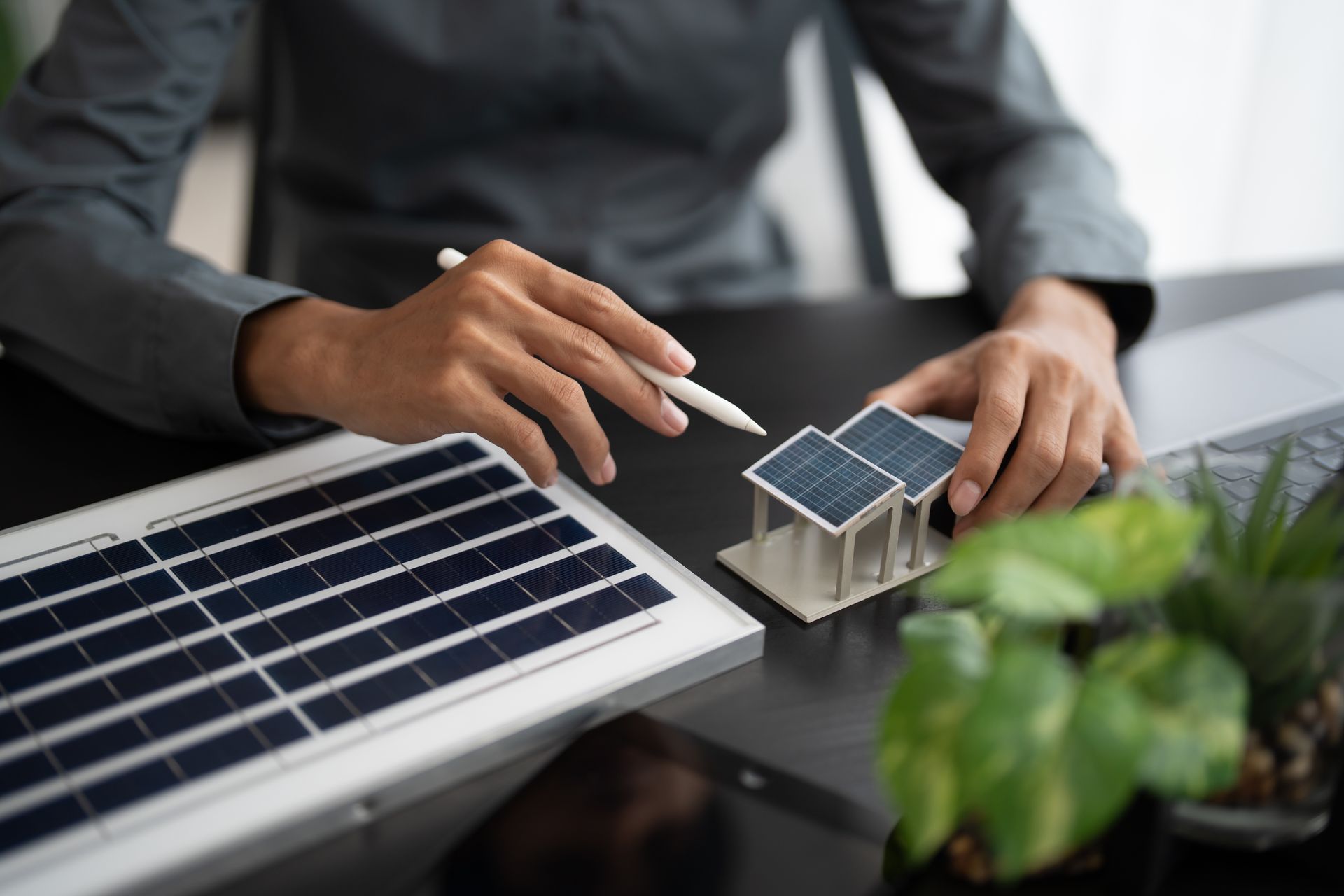 A person is sitting at a table holding a model of a solar panel and a pen.