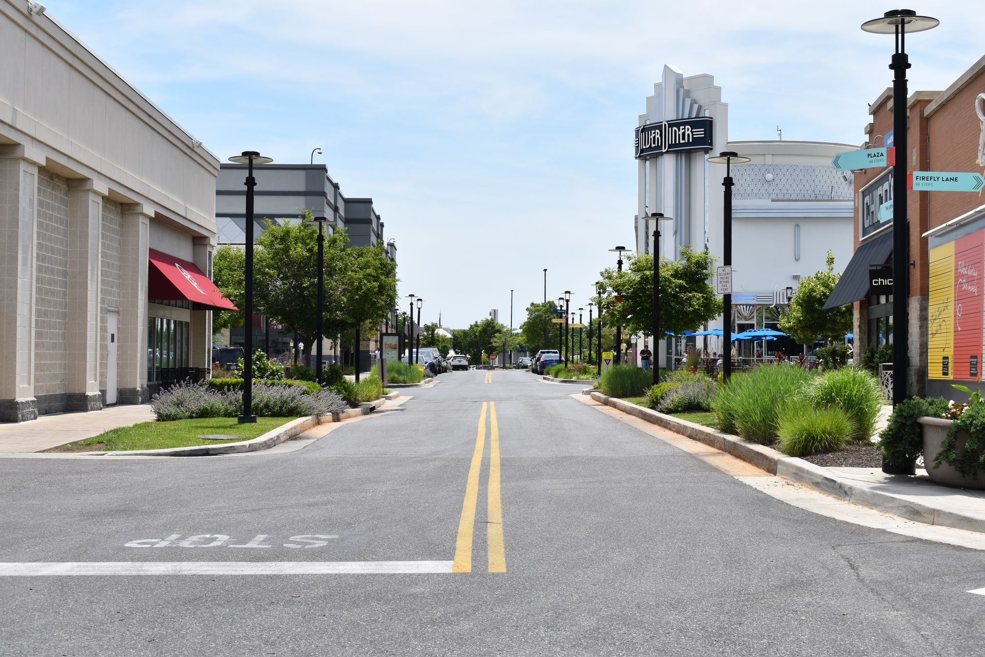 A shopping center street view with landscaping on either curb