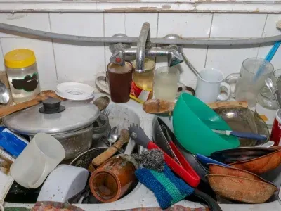 Évier de cuisine sale débordant de vaisselle et d'ustensiles.