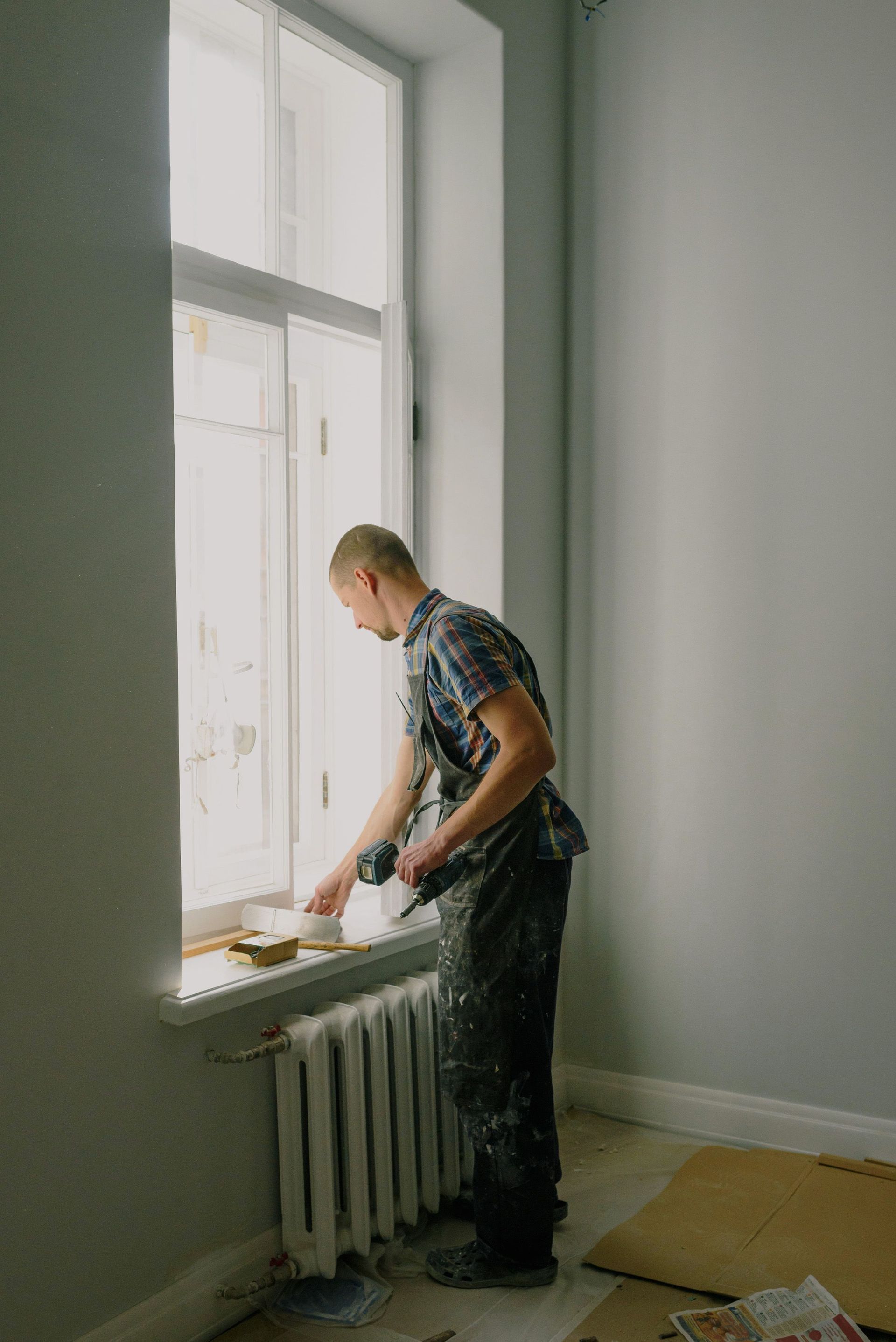 Un homme passe l'aspirateur dans un bureau moquetté avec un aspirateur dorsal. La pièce est meublée d'une table de conférence et de chaises.
