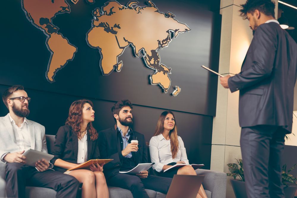 A Group of Business People Are Sitting on a Couch in Front of a Map of the World — Search Partners in Darwin, NT