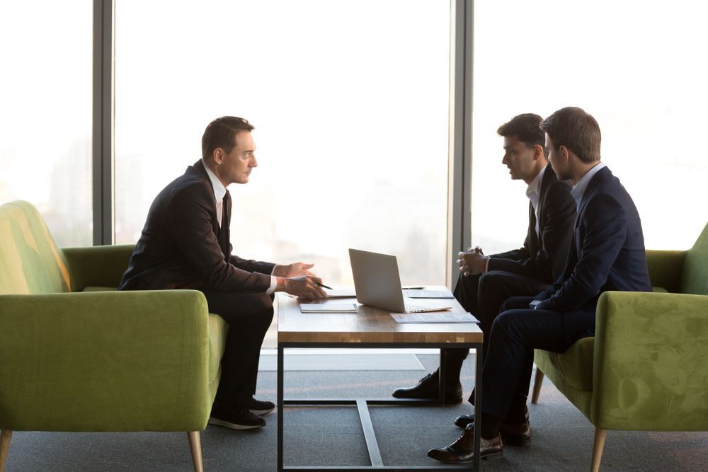 A Group of Businessmen Are Sitting Around a Table With a Laptop — Search Partners in Hobart, TAS