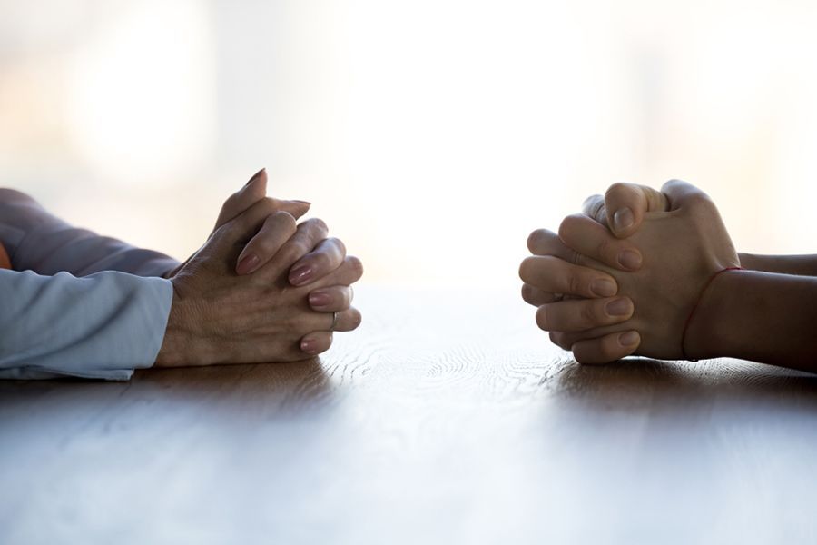 Two People Are Sitting at a Table With Their Hands Folded in Prayer — Search Partners in Melbourne, VIC