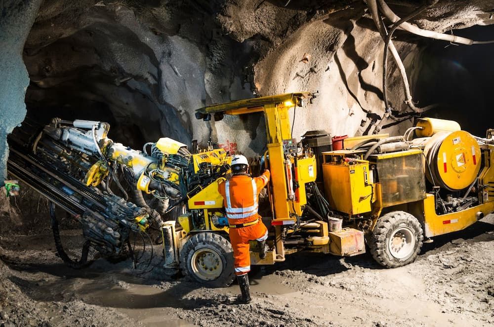 Worker in Orange Safety Gear Operates a Yellow Drilling Machine — Search Partners in Melbourne, VIC