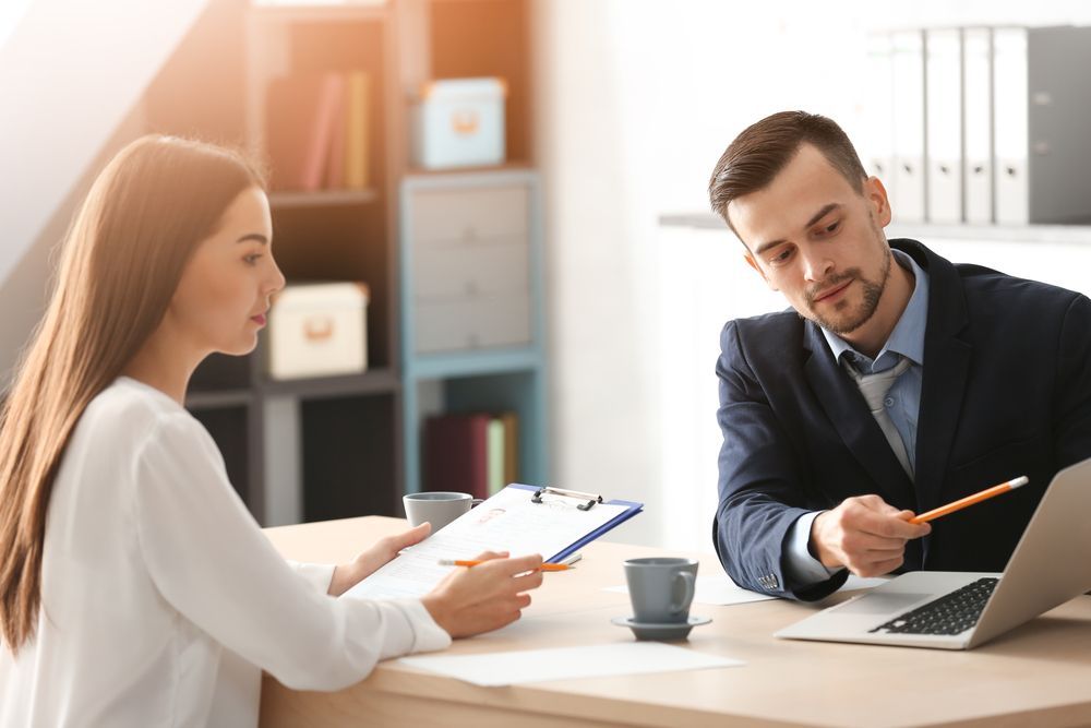 Woman and Man at Desk in Office, Reviewing Documents and Laptop — Search Partners in Melbourne, VIC