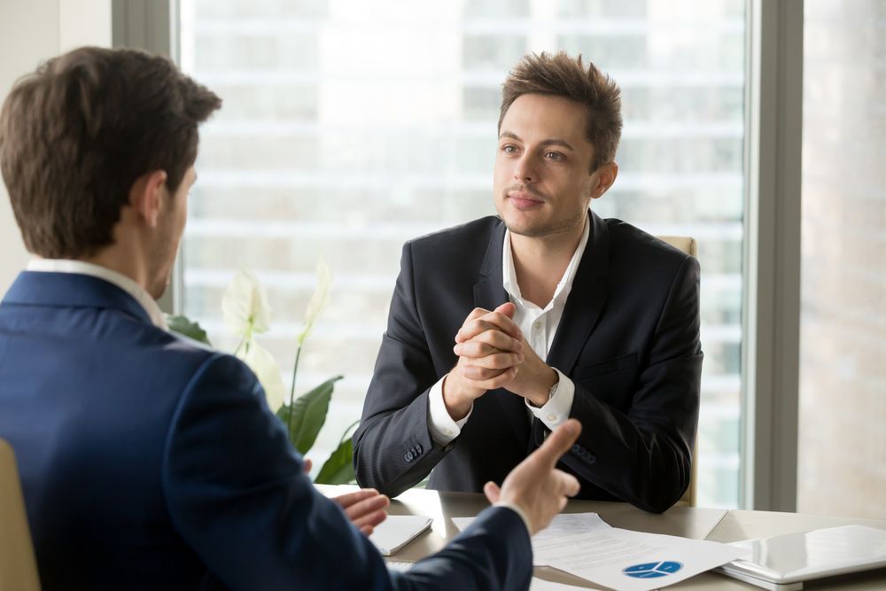 Two Men Are Sitting at a Table Having a Conversation — Search Partners in Canberra, ACT