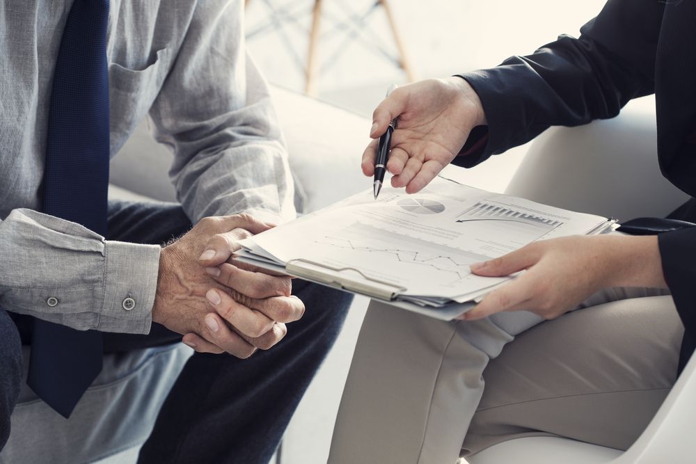 Man signing document presented by person in business attire — Search Partners in Brisbane, QLD