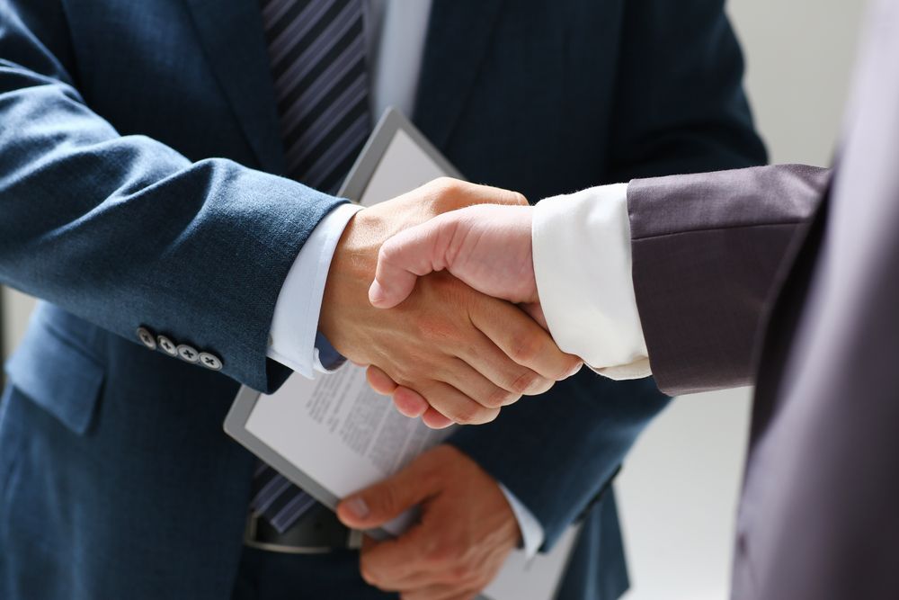 Two men in suits shaking hands. One holds a clipboard — Search Partners in Darwin, NT