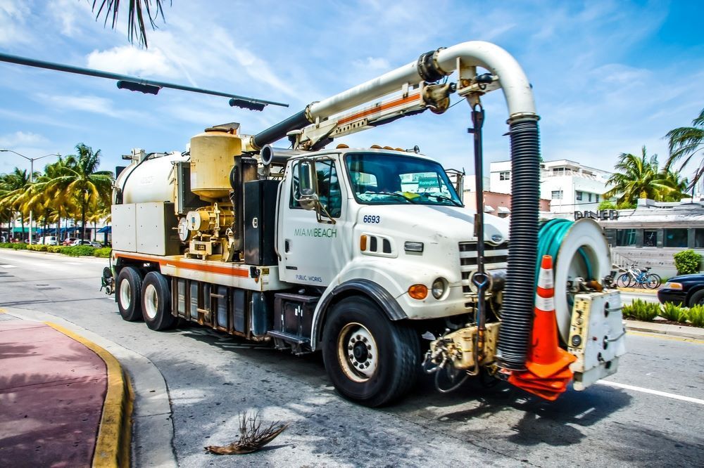 A White Vacuum Truck is Driving Down a City Street — Search Partners in Melbourne, VIC