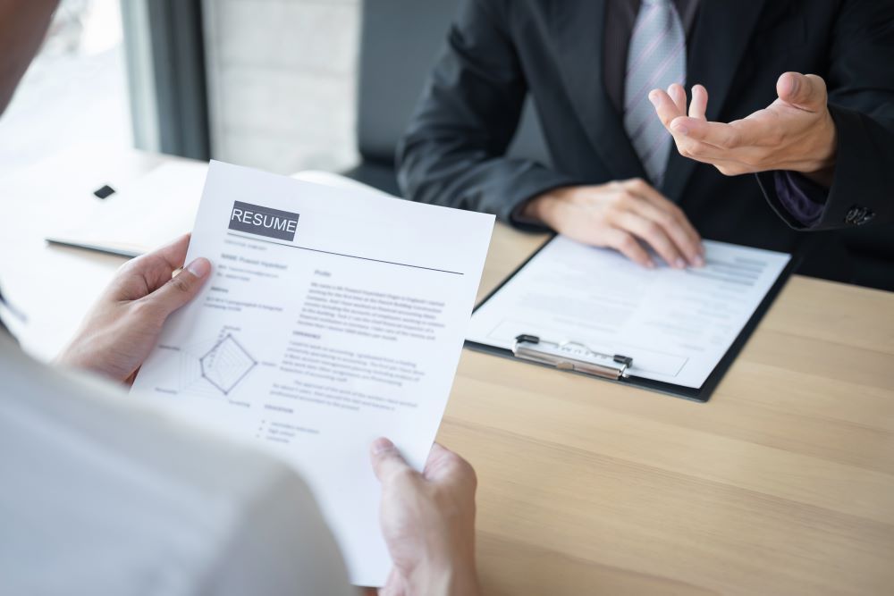 A Man is Holding a Resume in Front of a Woman During a Job Interview — Search Partners in Adelaide, SA
