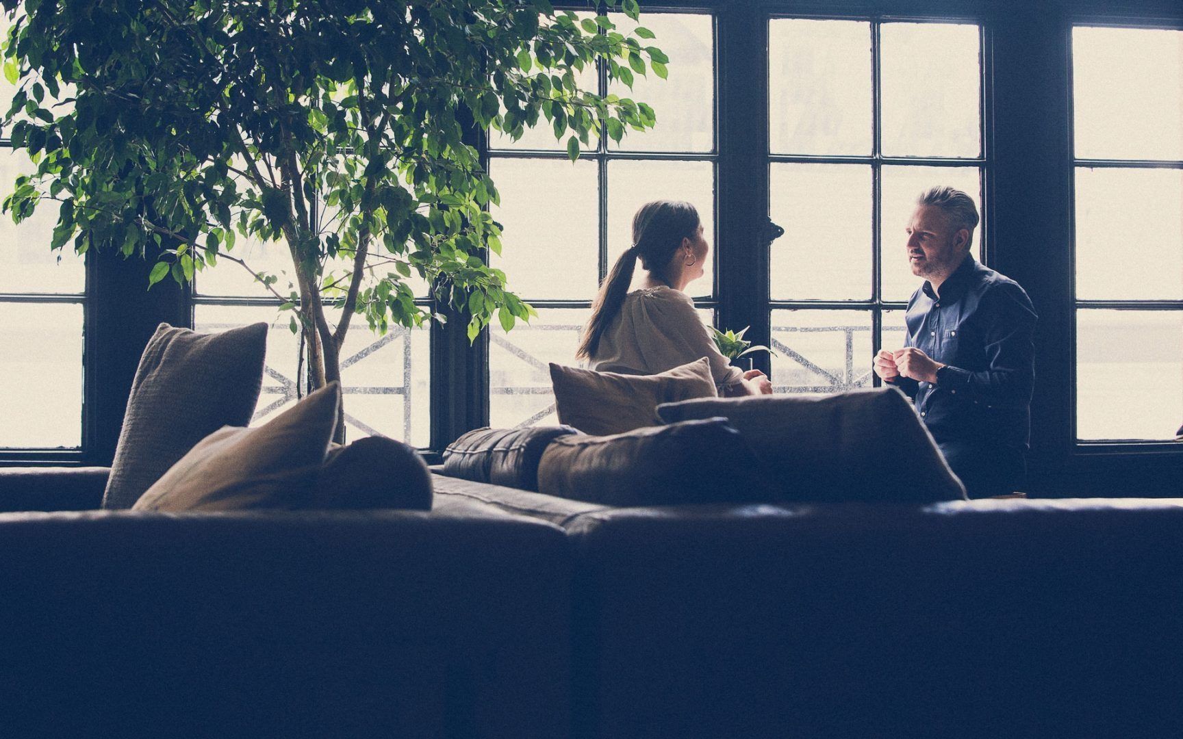 A Man and a Woman Are Sitting on a Couch in Front of a Window — Search Partners in Darwin, NT