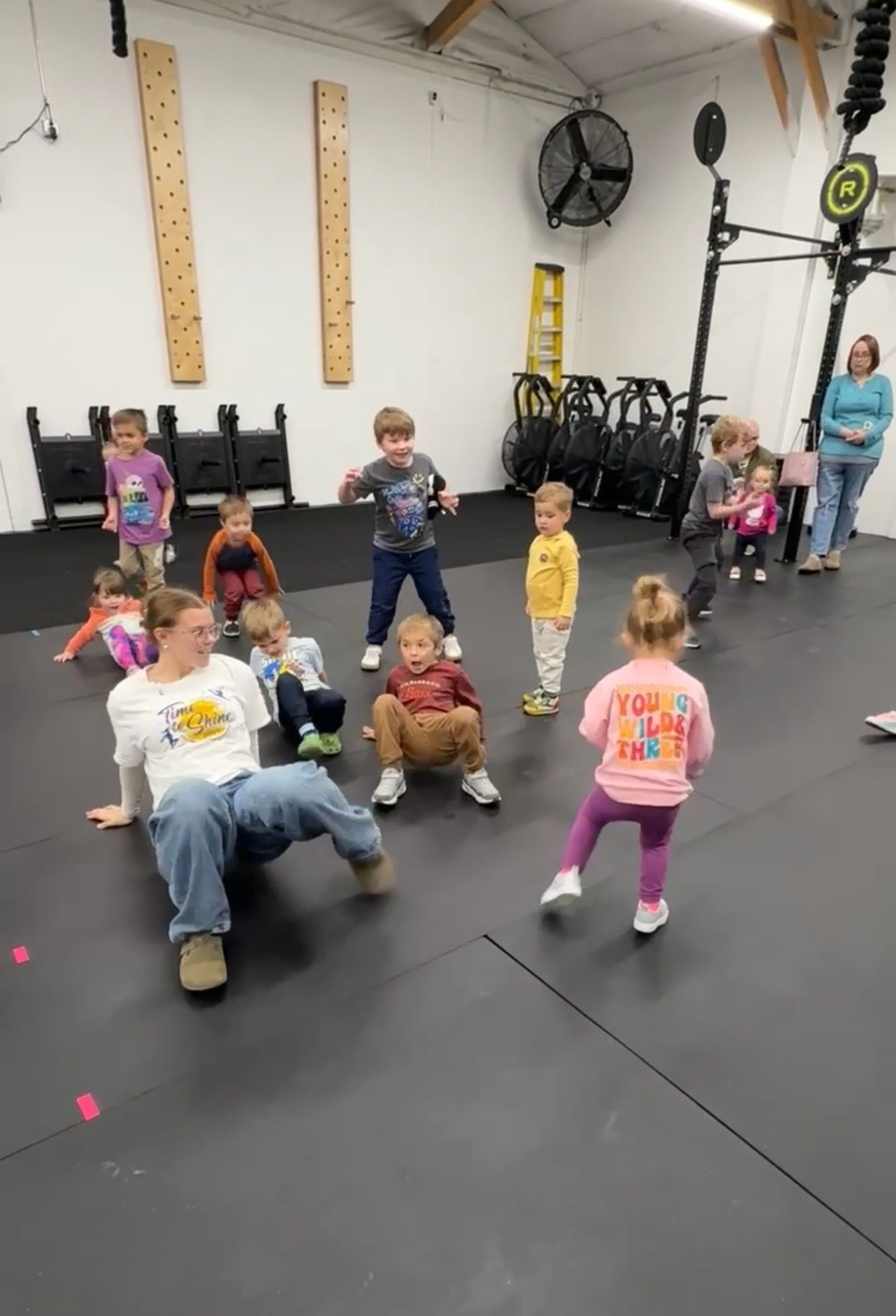 Children exercising in a gym, spaced apart with an instructor in front on a black floor at Everyday Strength, a gym in Wenatchee, WA