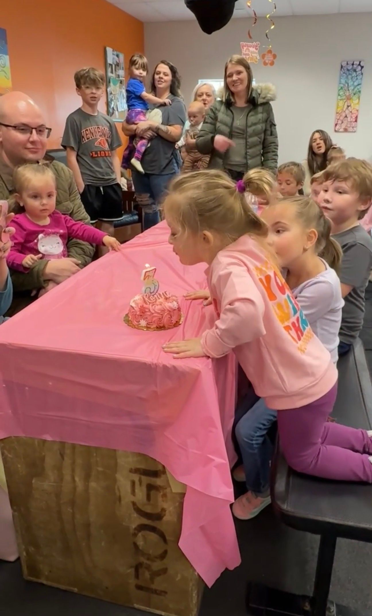 Children gathered around a pink-covered birthday table, watching a child blow out candles on a cake at Everyday Strength, a gym in Wenatchee, WA