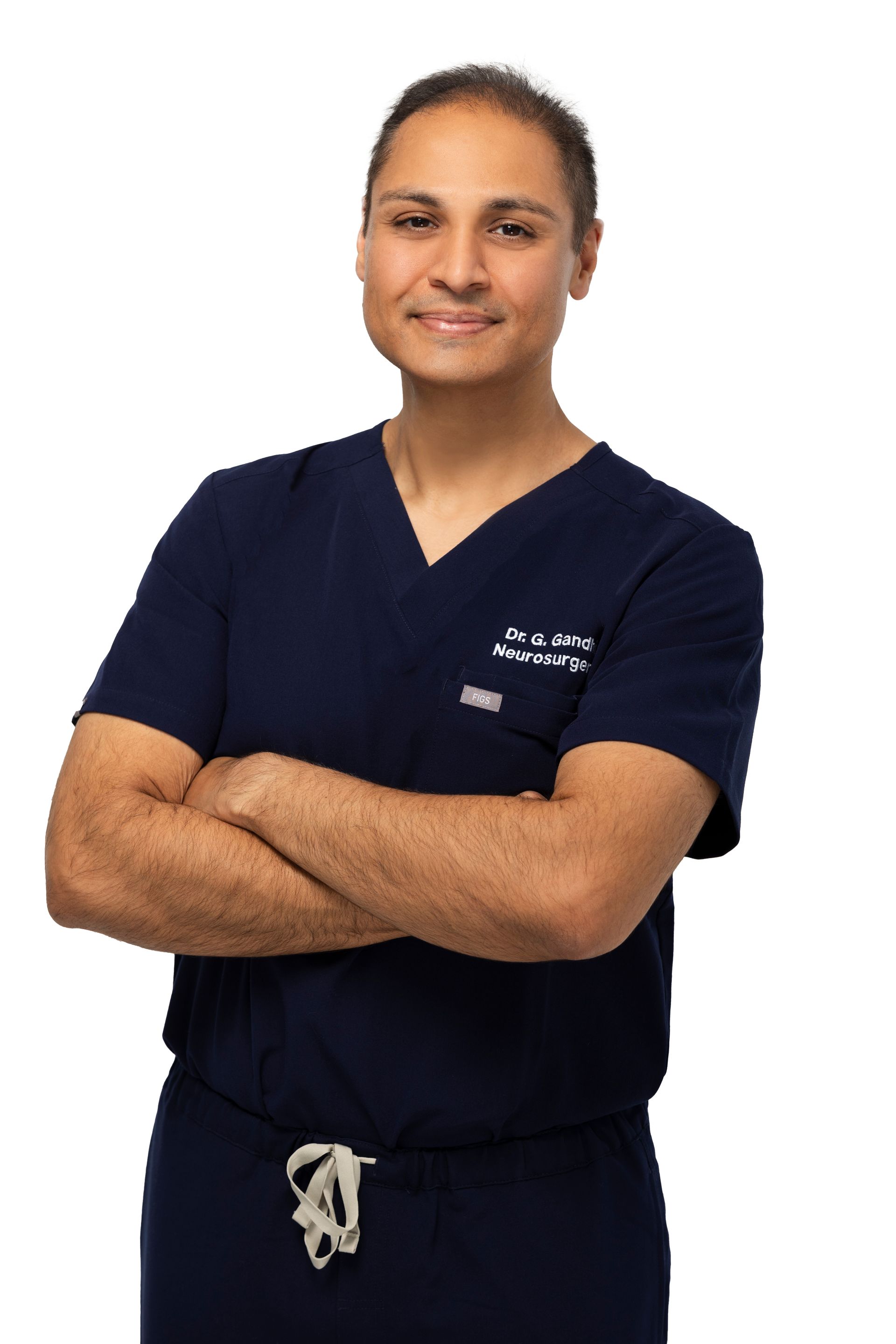 Healthcare worker in navy scrubs standing with arms crossed, smiling against a white background