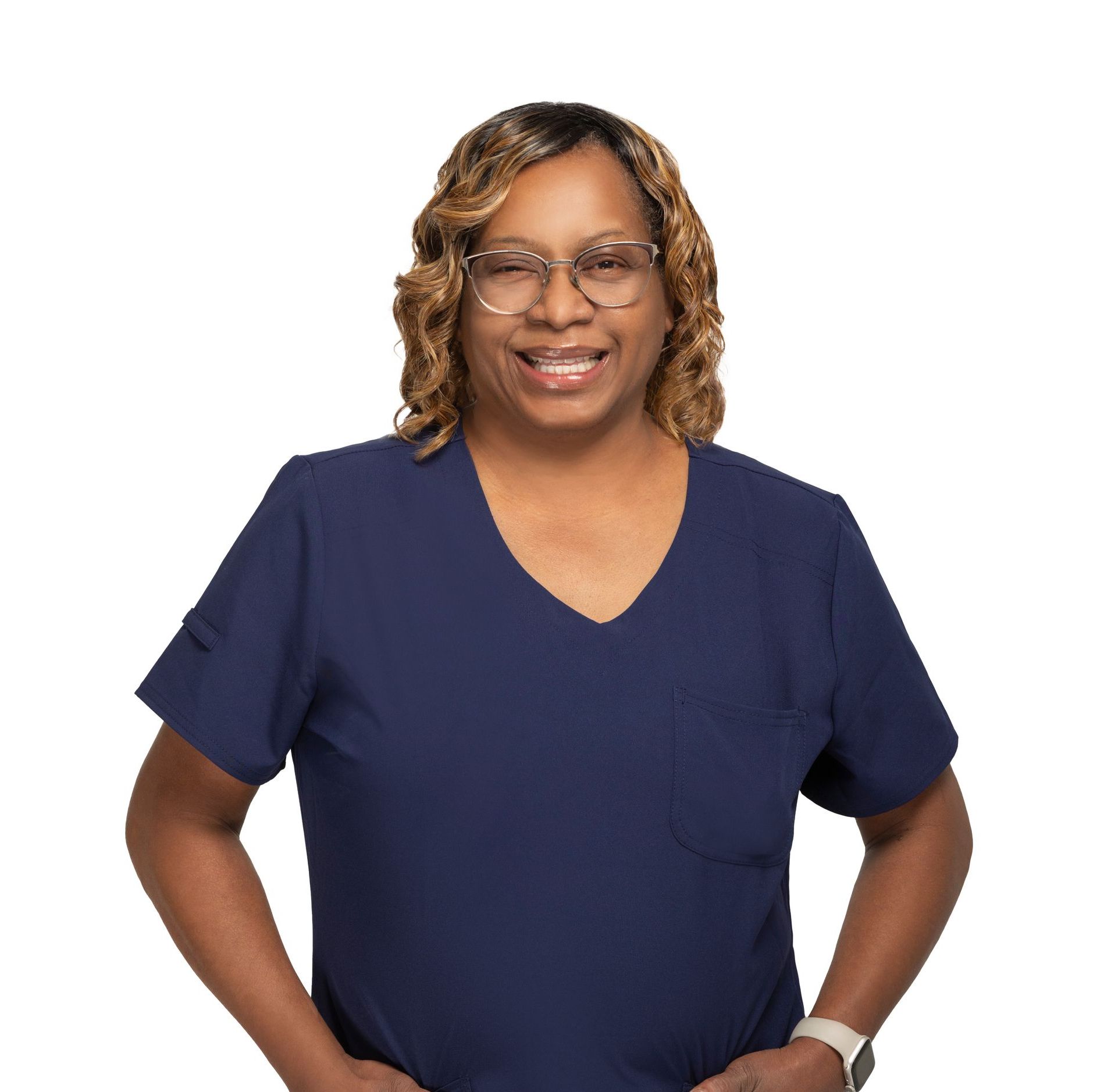 Smiling woman in navy scrub top with glasses, standing against a white background.