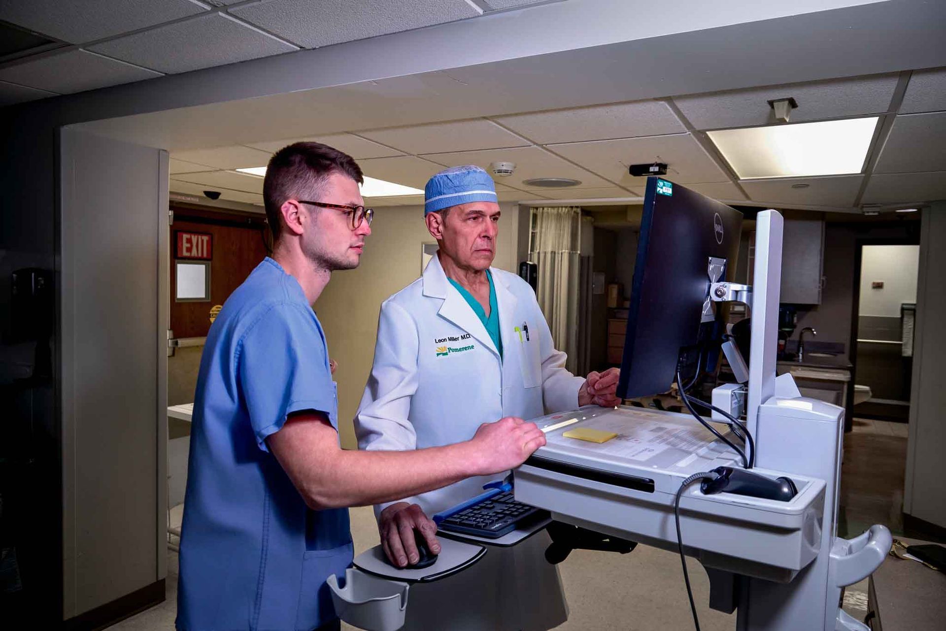 Two medical professionals reviewing a computer monitor in a hospital setting. 