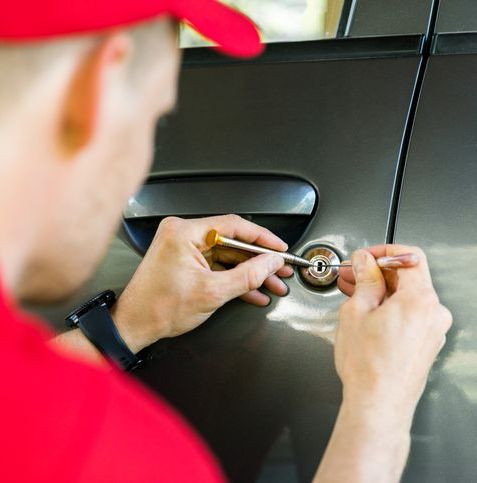 Locksmith opening car door with lockpicker