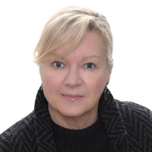 Studio portrait of a blonde woman in a dark sweater against a white background