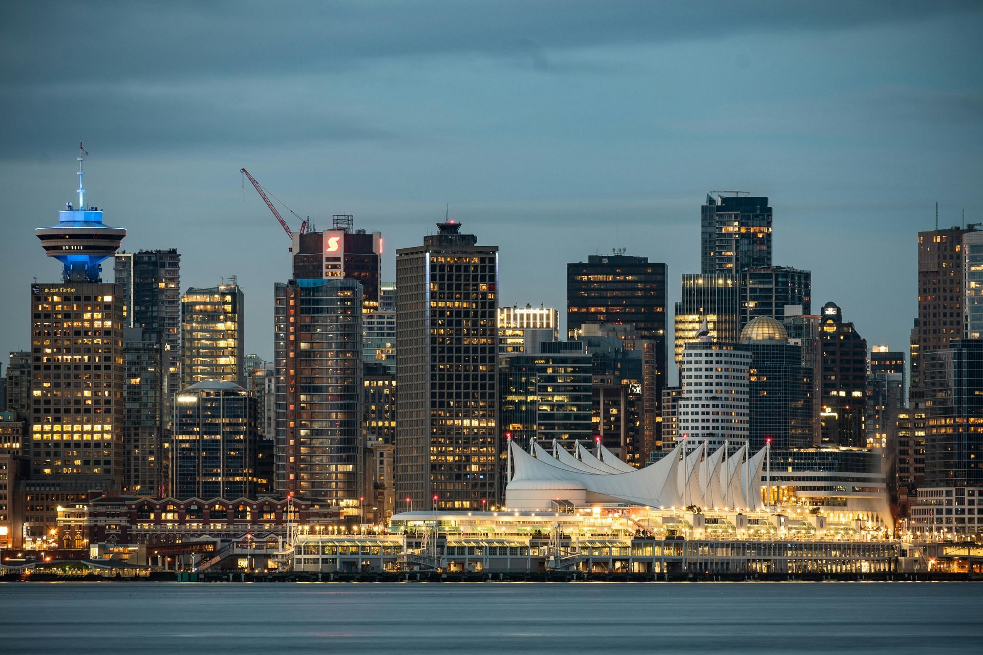 A city skyline at night with a large body of water in the foreground.
