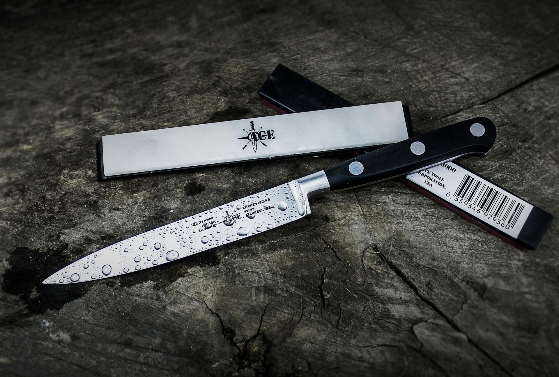 Two kitchen knives on a rough stone surface, one blade showing black splatter and a barcode tag