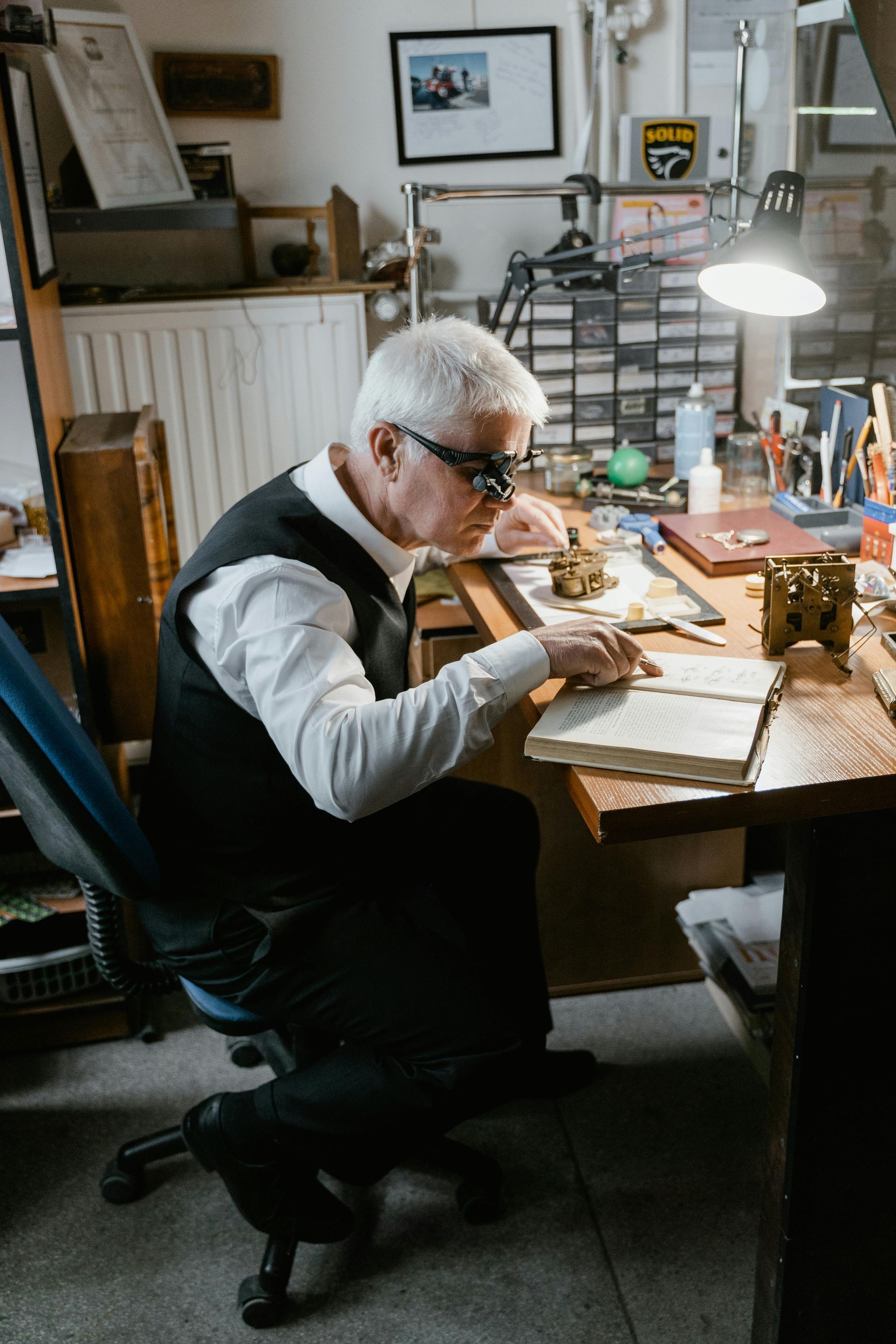 An older man is sitting at a desk in a workshop doing due diligence