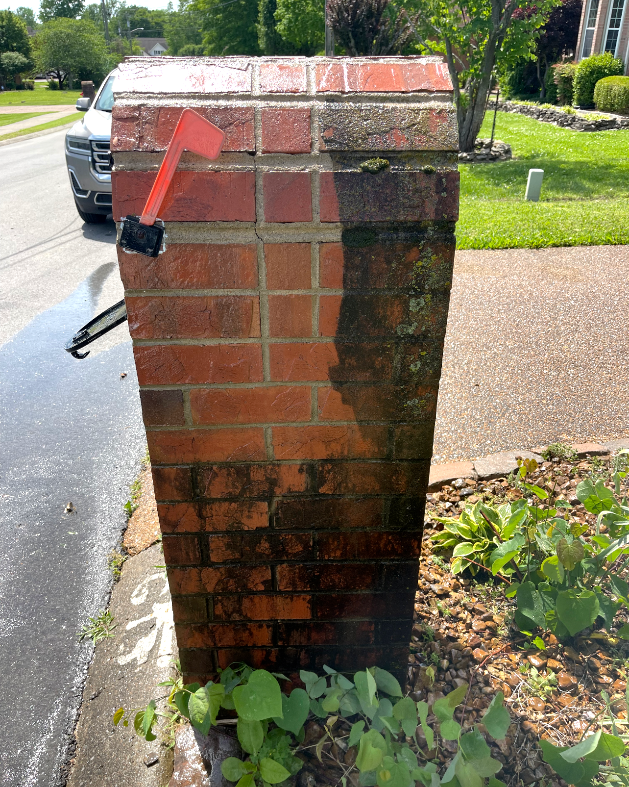 A man is cleaning a brick wall with a high pressure washer.