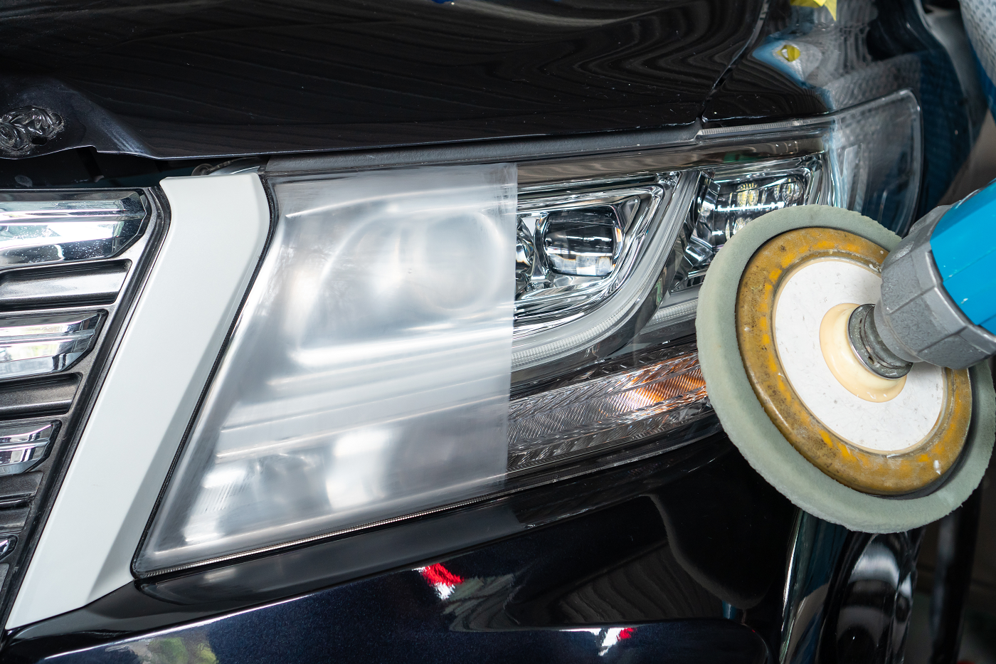 A person is polishing the headlights of a car.