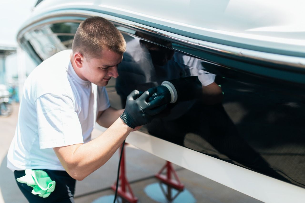 A man is polishing a boat with a machine.